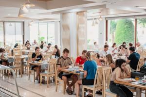 a group of people sitting at tables in a restaurant at Hotel Mediterrane in Sarandë