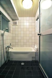 a bathroom with a tub and a glass shower door at Guest House Bokuyado in Kyoto