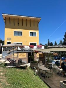 a building with a deck with tables and chairs at Chalet Jaune Le GRAND SOM in Sarcenas
