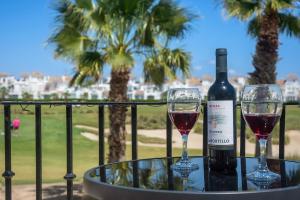 a bottle of wine and two glasses on a table at Townhouse overlooking golf course in Las Armeras