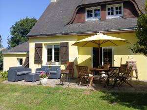 a patio with a table and chairs and an umbrella at Chambre d hote bucolique in Mahalon