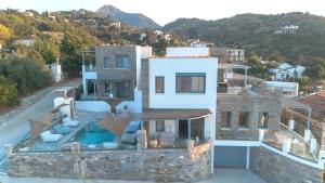 a villa with a swimming pool on a hill at Sofrano Luxury Apartments in Evdilos