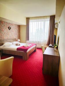 a hotel room with a large bed and a table at Hotel Olimp in Cluj-Napoca