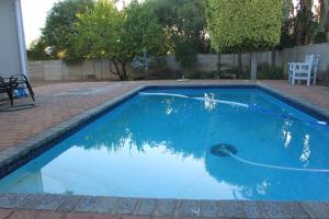 a swimming pool with blue water in a yard at The Alchemist's Place in Oudtshoorn