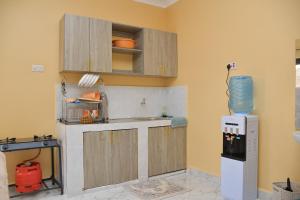 a kitchen with wooden cabinets and a refrigerator at Maria Villa Studio in Voi