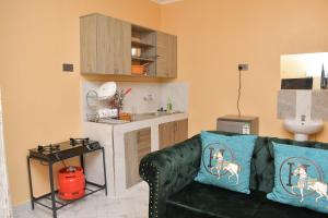 a living room with a black couch and a kitchen at Maria Villa Studio in Voi