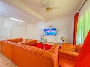 a living room with orange couches and a red rug at Oceana Villa in Mombasa