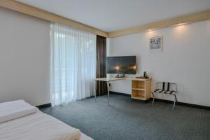 a hotel room with a desk and a television at Hotel Mondial Comfort - Frankfurt City Centre in Frankfurt