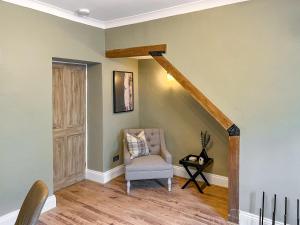 a living room with a chair and a staircase at Olive Cottage in Barnard Castle