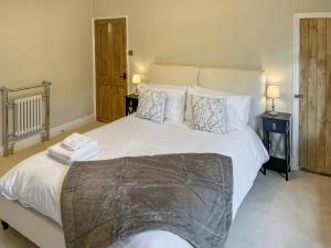 a bedroom with a large bed with white sheets and pillows at Olive Cottage in Barnard Castle