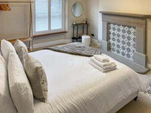 a bedroom with two white beds and a fireplace at Olive Cottage in Barnard Castle