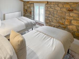 a bedroom with two beds and a stone wall at Olive Cottage in Barnard Castle +12 photos