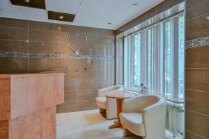 a bathroom with two chairs and a sink and a shower at Hotel Mondial Comfort - Frankfurt City Centre in Frankfurt +45 photos