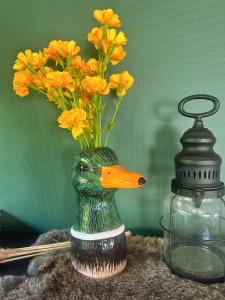 a vase with yellow flowers in it next to a bottle at Rustiek Boschalet Sven Veluwe met Omheinde Tuin in Putten