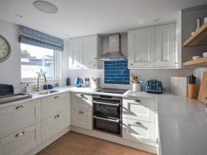 a kitchen with white cabinets and a sink and a window at Fuchsia Cottage in Saint Mawes