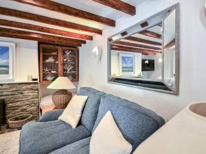 a living room with a blue couch and a mirror at Fuchsia Cottage in Saint Mawes