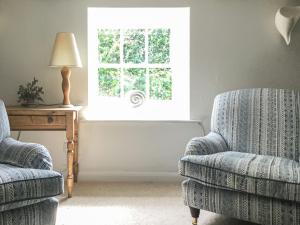 a living room with two chairs and a window at Fuchsia Cottage in Saint Mawes