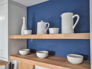 a shelf with white vases and bowls on it at Fuchsia Cottage in Saint Mawes +10 photos