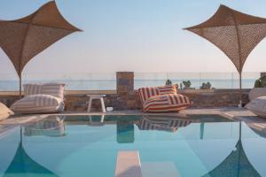 a swimming pool with two lounge chairs and umbrellas at Sofrano Luxury Apartments in Evdilos