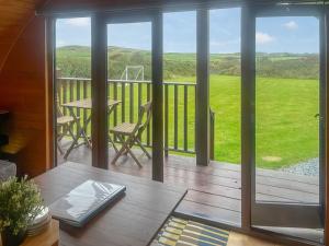 a screened porch with a table and chairs on a deck at Pencaerau Pods - Tudwal Pod in Pwllheli