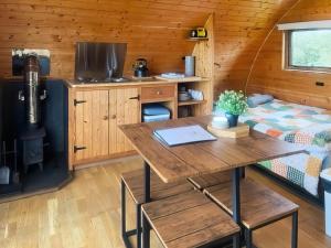 a kitchen with a table and a bed in a room at Pencaerau Pods - Tudwal Pod in Pwllheli