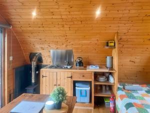 a kitchen in a wooden cabin with a table at Pencaerau Pods - Tudwal Pod in Pwllheli
