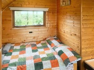 a bedroom with a bed in a log cabin at Pencaerau Pods - Tudwal Pod in Pwllheli