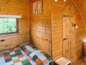 a bedroom with a bed in a log cabin at Pencaerau Pods - Tudwal Pod in Pwllheli +6 photos