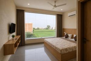 a bedroom with a bed and a large window at Hotel Olive Sunny Enclave, Near Airport Road, Mohali in Kharar