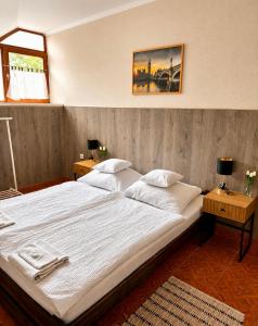 a large white bed in a bedroom with two tables at Muskátli Panzió és Étterem in Újhartyán