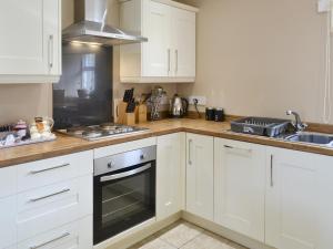 a kitchen with white cabinets and a stove top oven at Fordson in Warenford