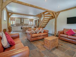 a living room with leather furniture and a kitchen at Y Llaethdy - Uk49916 in Penclawdd