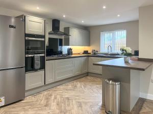 a kitchen with white cabinets and stainless steel appliances at Barncroft Retreat - Uk51693 in Flimby