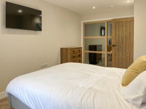 a bedroom with a white bed with a flat screen tv at Barncroft Retreat - Uk51693 in Flimby
