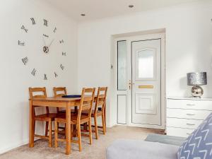 a dining room table with chairs and a clock on the wall at Chalet 4 in Flookburgh