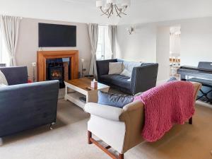 a living room with a couch and a piano at 2 The Langhouse in Inverkip