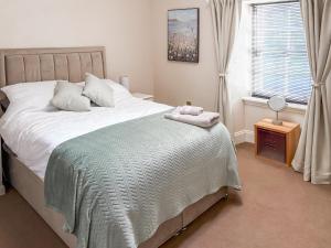 a bedroom with a bed with a blanket and a window at 2 The Langhouse in Inverkip