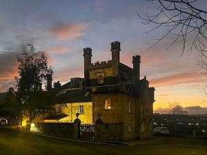 an old house with a sunset in the background at 2 The Langhouse in Inverkip +5 photos