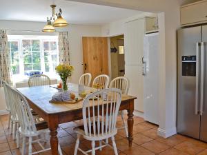 a kitchen and dining room with a wooden table and chairs at Woodbrook Cottage in Bridport