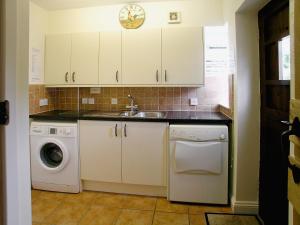 a kitchen with a sink and a washing machine at Woodbrook Cottage in Bridport +26 photos