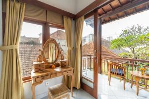 a room with a balcony with a mirror and a table at Ubud Heritage Stay by Dhananjaya Hospitality in Ubud