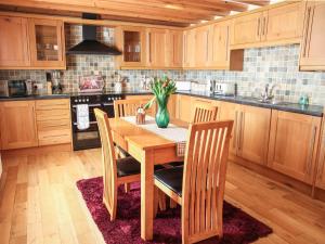 a kitchen with a wooden table with chairs and a vase of flowers at Hill Cottage in Ardmair