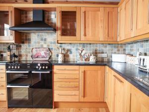 a kitchen with wooden cabinets and a black stove at Hill Cottage in Ardmair