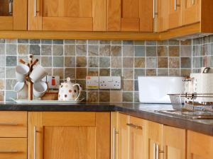 a kitchen with wooden cabinets and a counter top at Hill Cottage in Ardmair