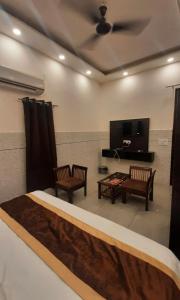 a bedroom with a bed and two chairs and a flat screen tv at Hotel Park Blu in Pānīpat