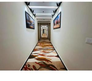 a hallway with a carpet with paintings on the walls at Evara Exotica in Darbhanga