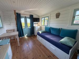 a room with a blue couch in a tiny house at La Roulotte à Raven in Le Houga