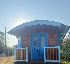 a small house with a blue door and a porch at La Roulotte à Raven in Le Houga +3 photos