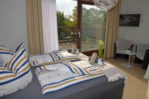 ein Schlafzimmer mit einem Bett mit gestreiften Kissen und einem Balkon in der Unterkunft Hotel Neptuns Ankerplatz & Zur Seerobbe in Cuxhaven + 73 Fotos