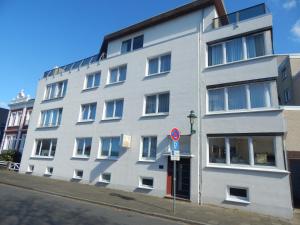 ein weißes Gebäude an einer Straßenseite in der Unterkunft Hotel Neptuns Ankerplatz & Zur Seerobbe in Cuxhaven
